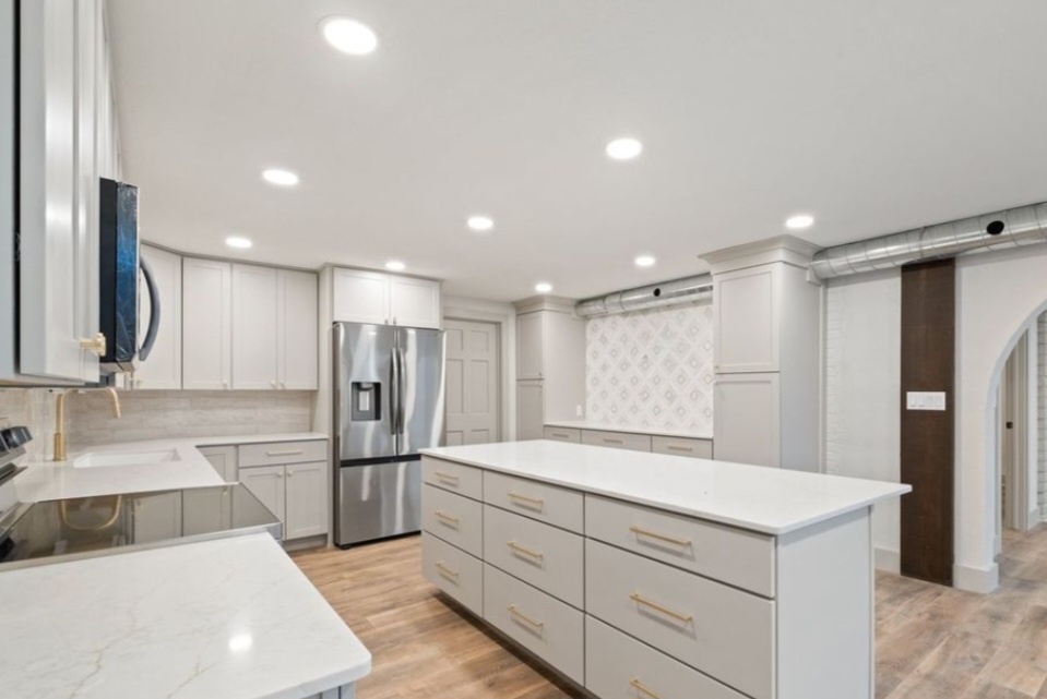 A modern white kitchen with recessed ceiling lighting